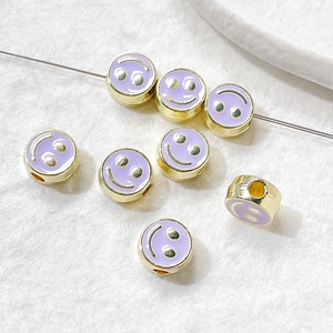 Macro shot of purple enamel smiley face beads with gold base for DIY jewelry making