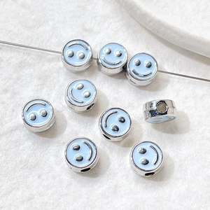 Macro view of light blue enamel smiley face beads for DIY jewelry making and crafts