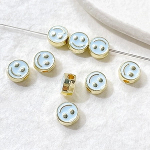 Macro detail of light blue enamel smiley face beads for DIY jewelry making