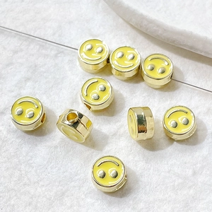 Macro shot of gold-plated yellow enamel smiley face beads for DIY jewelry making