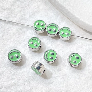 Green enamel smiley face beads on wire showing DIY bracelet jewelry components