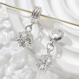 Macro detail of silver hollow cage pendant charm with sparkling cubic zirconia stone inlay
