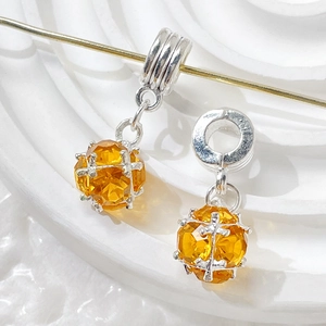 Macro shot of silver-tone charms with sparkling orange cubic zirconia in a cage setting