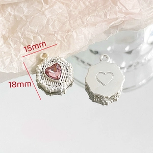 Macro detail of 15x18mm silver alloy heart pendant with pink gemstone and relief texture