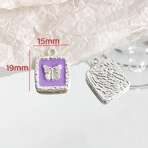 Detailed view of square purple butterfly pendants with silver relief and metallic texture