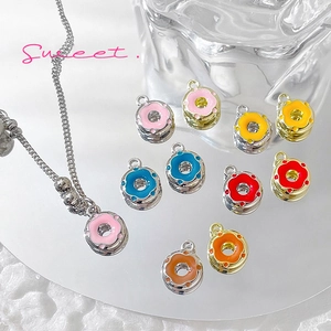 Colorful donut-shaped alloy pendants on silver chains over a soft white aesthetic backdrop