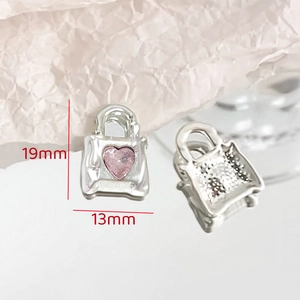 Detailed macro view of silver handbag charm with pink heart zircon and size markings