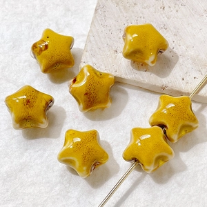 Macro detail of yellow ceramic star beads with speckled glaze for DIY jewelry making