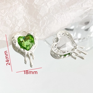 Detailed macro of a 24mm silver-toned heart pendant with a faceted green crystal inlay