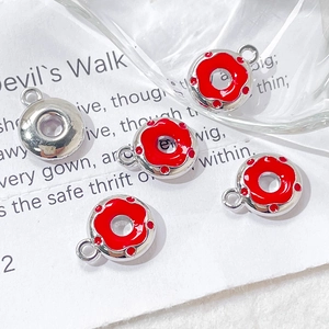 Macro shot of red enamel donut charms for DIY jewelry making on white literary background