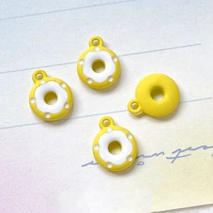 Detail von vier gelben Donut-Anhängern mit weißer Glasur für DIY-Schmuckprojekte