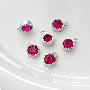 Detalle de colgantes redondos plateados con circonitas rojo rubí para hacer joyería