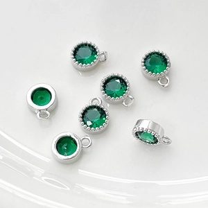 Detalle de dijes de circón verde esmeralda con marco plateado para joyería artesanal
