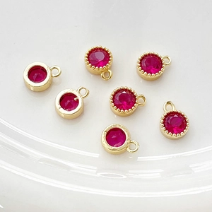 Detalle de dijes de rubí redondo bañados en oro de 14k con bordes lisos y de cuentas para joyería