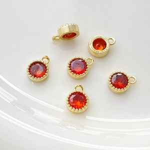 Detalle macro de seis colgantes redondos bañados en oro 14k con circonitas naranjas para joyería