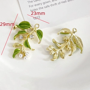 Dettaglio di ciondoli a foglia dorata con smalto verde, perle e cristalli per gioielli DIY