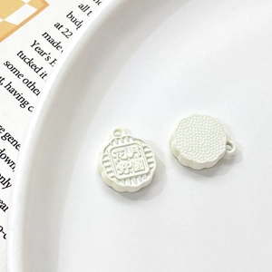 Detail of cream rabbit mooncake pendant with floral relief and top hanging metal loop