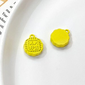 Macro view of yellow mooncake charm with floral engraving for DIY jewelry making