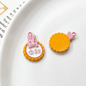 Detailed view of pink rabbit and yellow disc alloy charms for DIY jewelry making