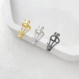 Detailed close-up of hollow 18K gold and silver lantern charms on a white stone display