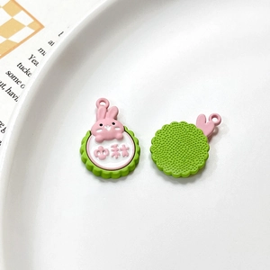 Detail of bunny charms for jewelry making, featuring pink rabbits on green bases
