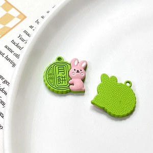 Macro detail of cartoon bunny mooncake alloy pendants showing front and back textures