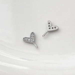 Macro detail of heart-shaped silver charms with cubic zirconia and twisted pin connectors