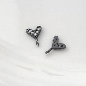 Detail of heart-shaped black metal jewelry charms with cubic zirconia inlay and twist texture