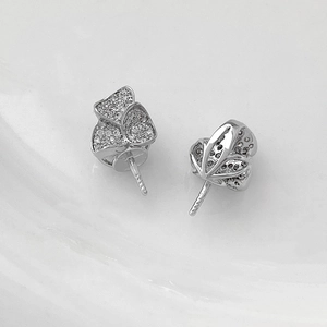 Macro detail of silver floral jewelry setting with pave-set crystals and mounting pin