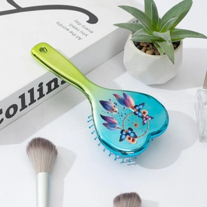Detail of heart-shaped hairbrush featuring butterfly and dreamcatcher graphic print