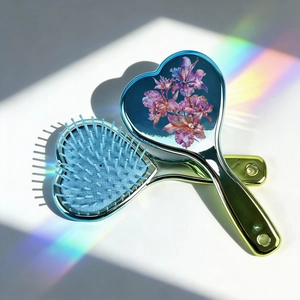 Detail of heart-shaped air cushion hairbrush with floral pattern and electroplated finish