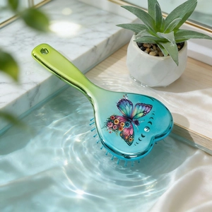 Detail of heart-shaped cushion hairbrush with butterfly print on blue water background