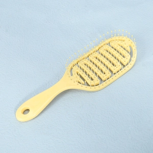 Detail of ergonomic handle and hollow honeycomb design of the yellow hairbrush