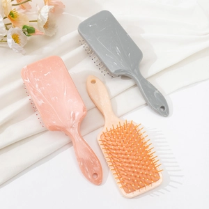 Three marble pattern air cushion hairbrushes in pink, grey and beige for scalp massage