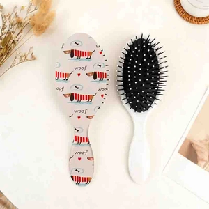 Détail d'une brosse à cheveux ovale avec motif de teckel et picots à pointes blanches