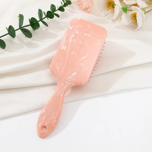Detailed view of pink marble air cushion hairbrush on white silk background with flowers