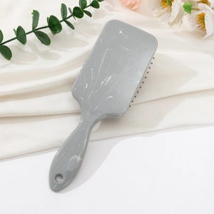 Detail of grey marble pattern hairbrush featuring massage bristles and a hanging hole