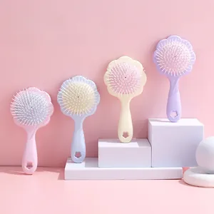 Gros plan de quatre brosses à cheveux fleurs macaron sur un présentoir rose pastel