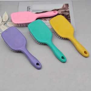 Colorful set of four mini air cushion massage hairbrushes in pink, purple, green and yellow