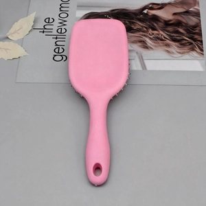 Detail of pink square cushion hairbrush with matte finish and hanging hole on handle