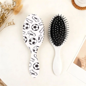 Detail view of two soccer printed oval hair brushes with soft massage bristles and white base