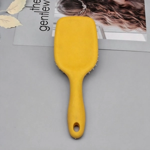 Detail view of the yellow hairbrush handle with a round hanging hole and sleek design