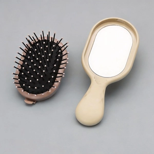 Detail of portable cushion hairbrush featuring massage bristles and a built-in makeup mirror