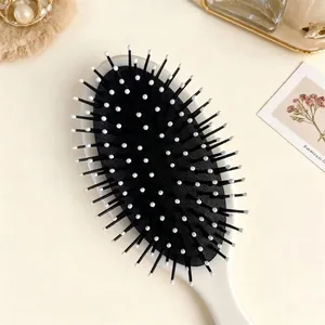 Oval soccer cushion hairbrush with ergonomic white handle and black massage bristles