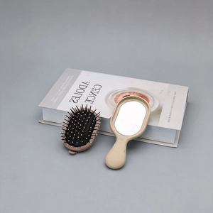 Portable folding hairbrush with massage cushion and mirror in a minimalist beige design