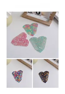 Detailed macro view of heart-shaped acetate hair combs in various marble and floral patterns