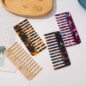 Wide-tooth acetate hair combs in four vibrant marble patterns on a wooden tray