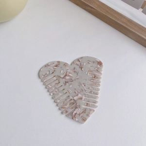 Macro shot of heart-shaped acetate hair comb with cream and brown marble texture