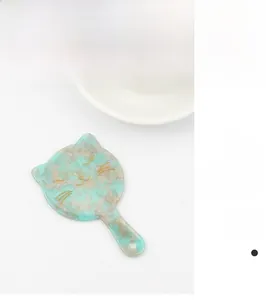 Dettaglio dello specchio a mano in acetato a forma di gatto con trama marmorea verde menta e oro
