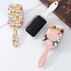 Set of three cute cartoon air cushion hair brushes with cat and owl prints on a white table